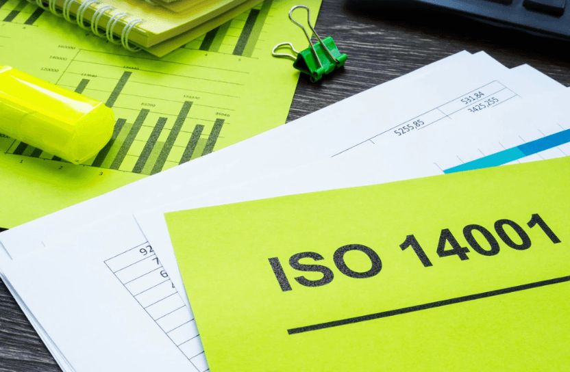 Papers on a table, a yellow one on top with the words "ISO 14001"