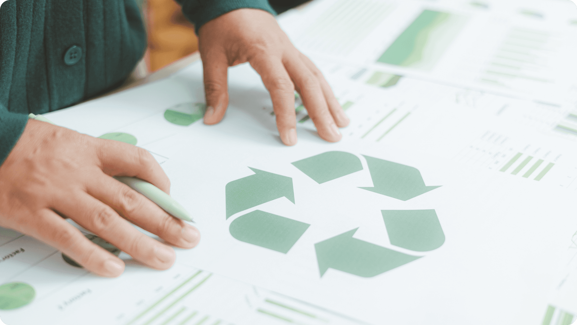 Hands and paper with recycling symbol.