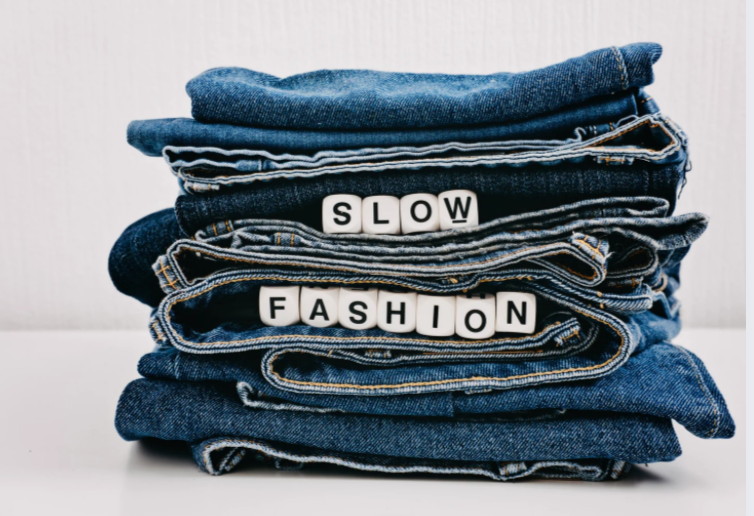 A stack of jeans, letters saying "slow fashion" in between.
