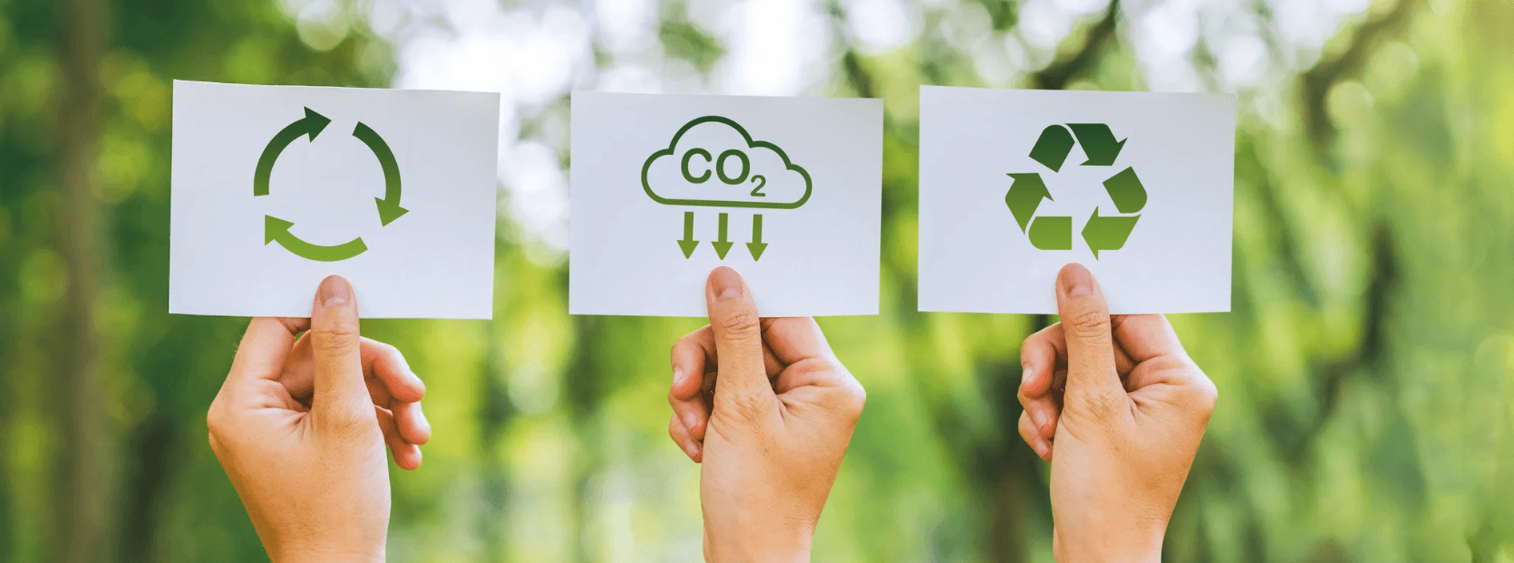 Hands holding papers with sustainability symbols.