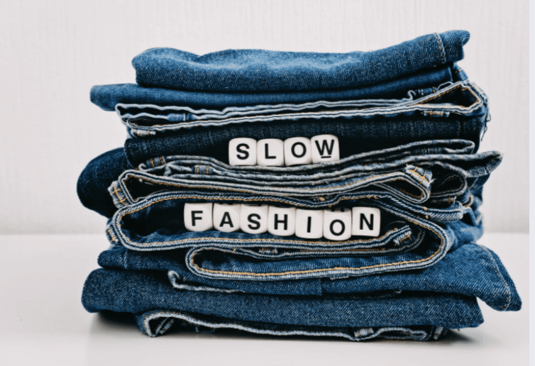 En hög med jeans och orden "Slow fashion".
